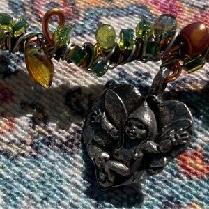 Whimsical handcrafted twisted wire necklace with charm of fairy baby on a leaf.